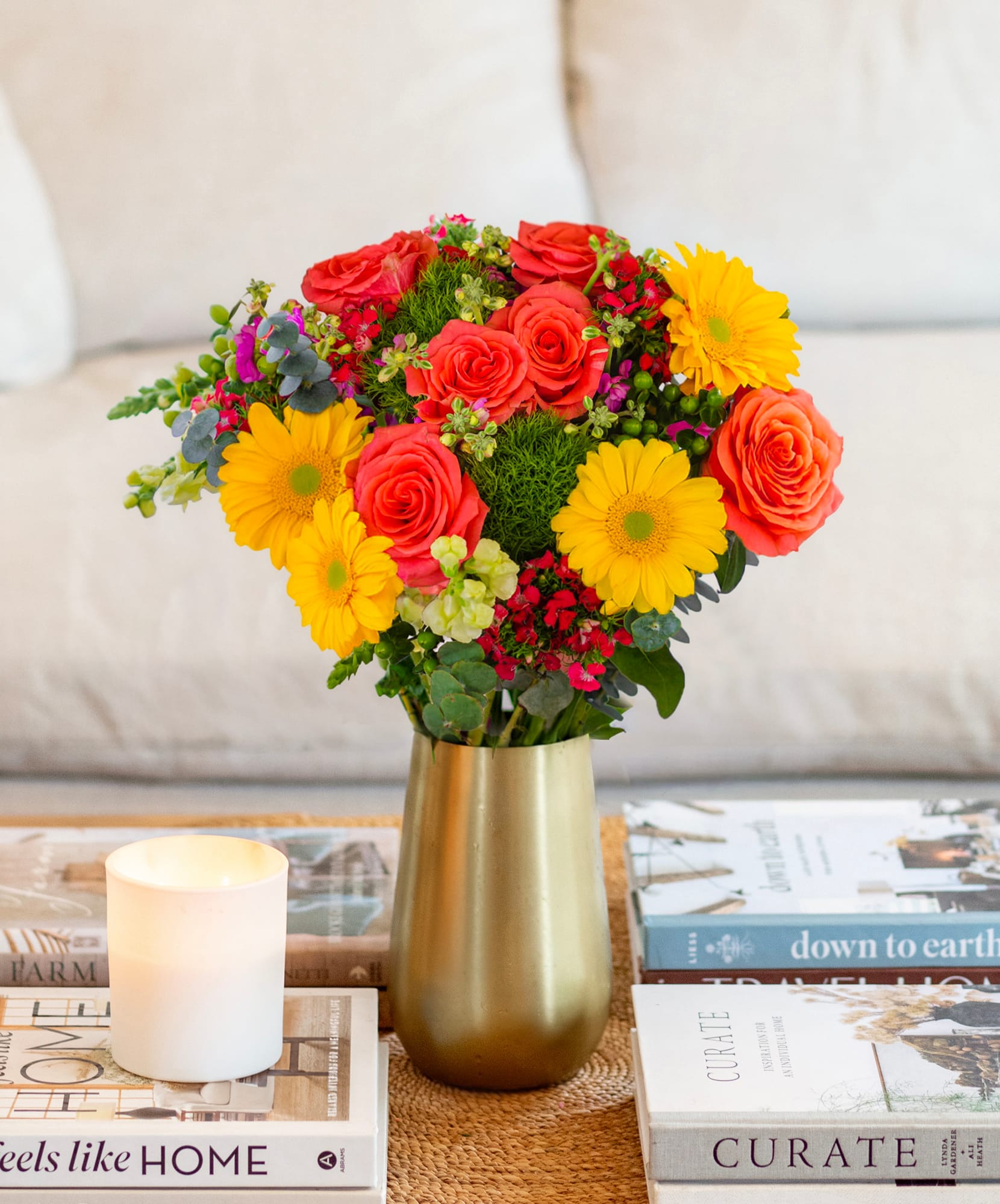 Bright floral bouquet featuring yellow gerbera daisies, orange roses, and lush greenery.